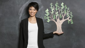 Happy Asian Business woman in front of chalk money tree drawing on blackboard.
