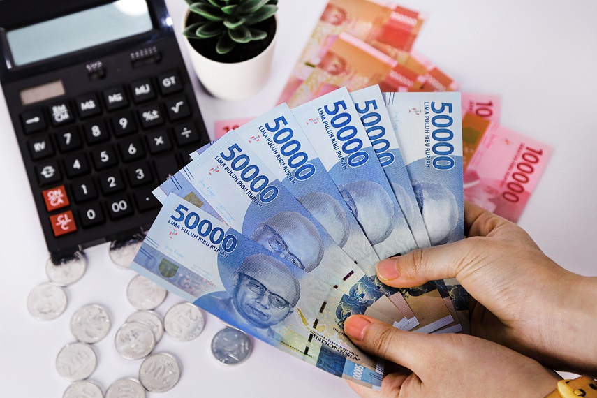 hands holding a bunch of Indonesian rupiah currencies with coins and paper currency background